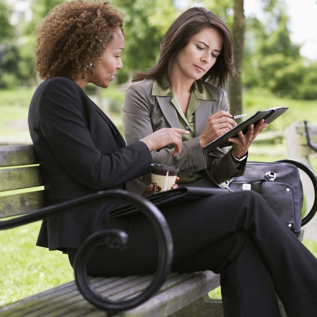 Two businesswomen sitting on a park bench
