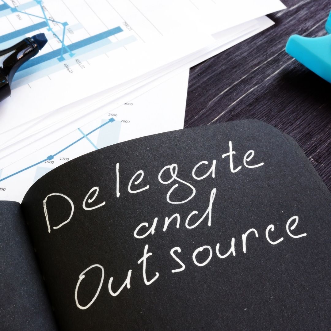 "Delegate and Outsource" written on a black notebook