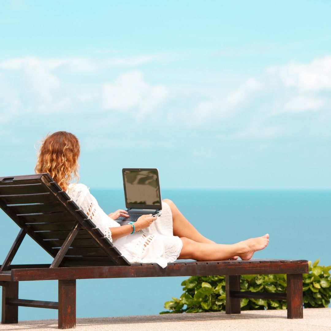 Woman on a chaise lounge working on a laptop