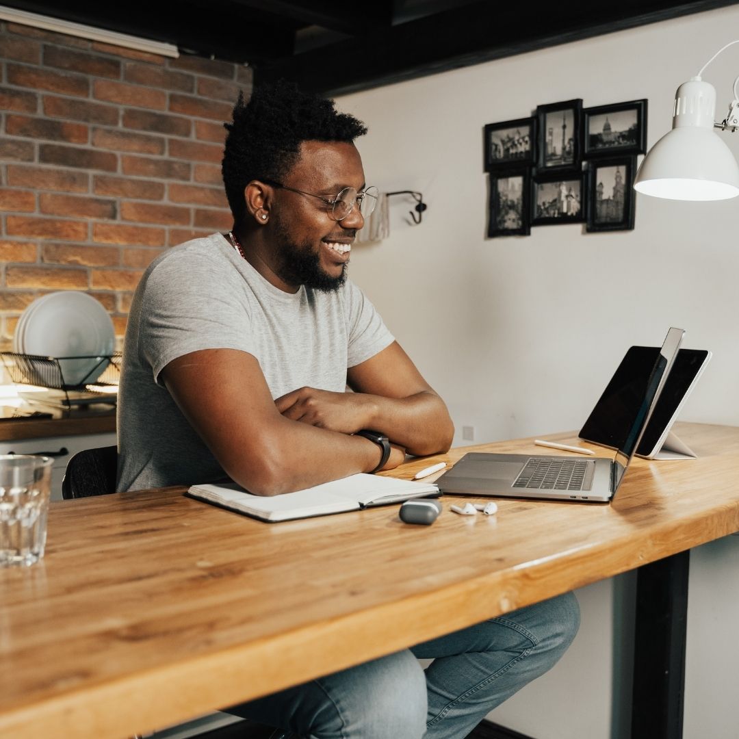 Smiling businessman working on a laptop at his kitchen table
