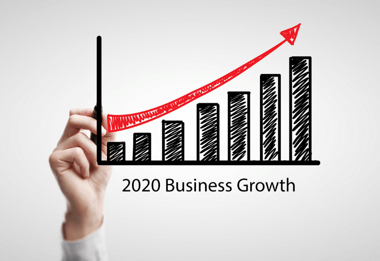 Hand holding a marker illustrating a graph with upward trend labeled "2020 Business Growth," representing business success and growth strategies relevant to Kristen David's coaching services.