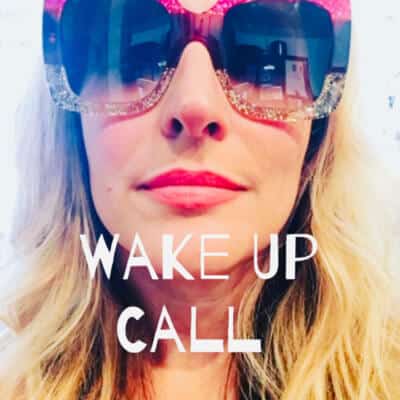 Woman wearing large, sparkly sunglasses with the text "WAKE UP CALL," reflecting a bold and motivational theme, relevant to Kristen David's coaching and mentoring services.