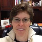 Coach Kristen smiling in an office setting, emphasizing trust, honesty, and excellence in business coaching at Upleveling Your Business.