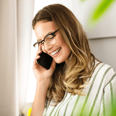 Smiling businesswoman wearing glasses and a striped shirt talking on the phone