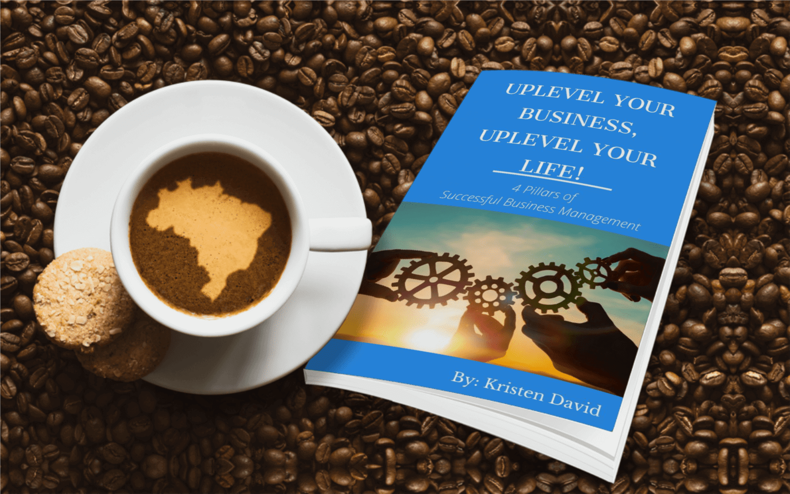 Cup of coffee with a map silhouette in the foam, beside two cookies and the book "Uplevel Your Business, Uplevel Your Life!" featuring gears and a sunset background, symbolizing business growth and personal development resources.