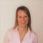 Coach Shannon from Upleveling Your Business, smiling and wearing a light pink shirt, representing the company's commitment to tailored coaching and excellence.