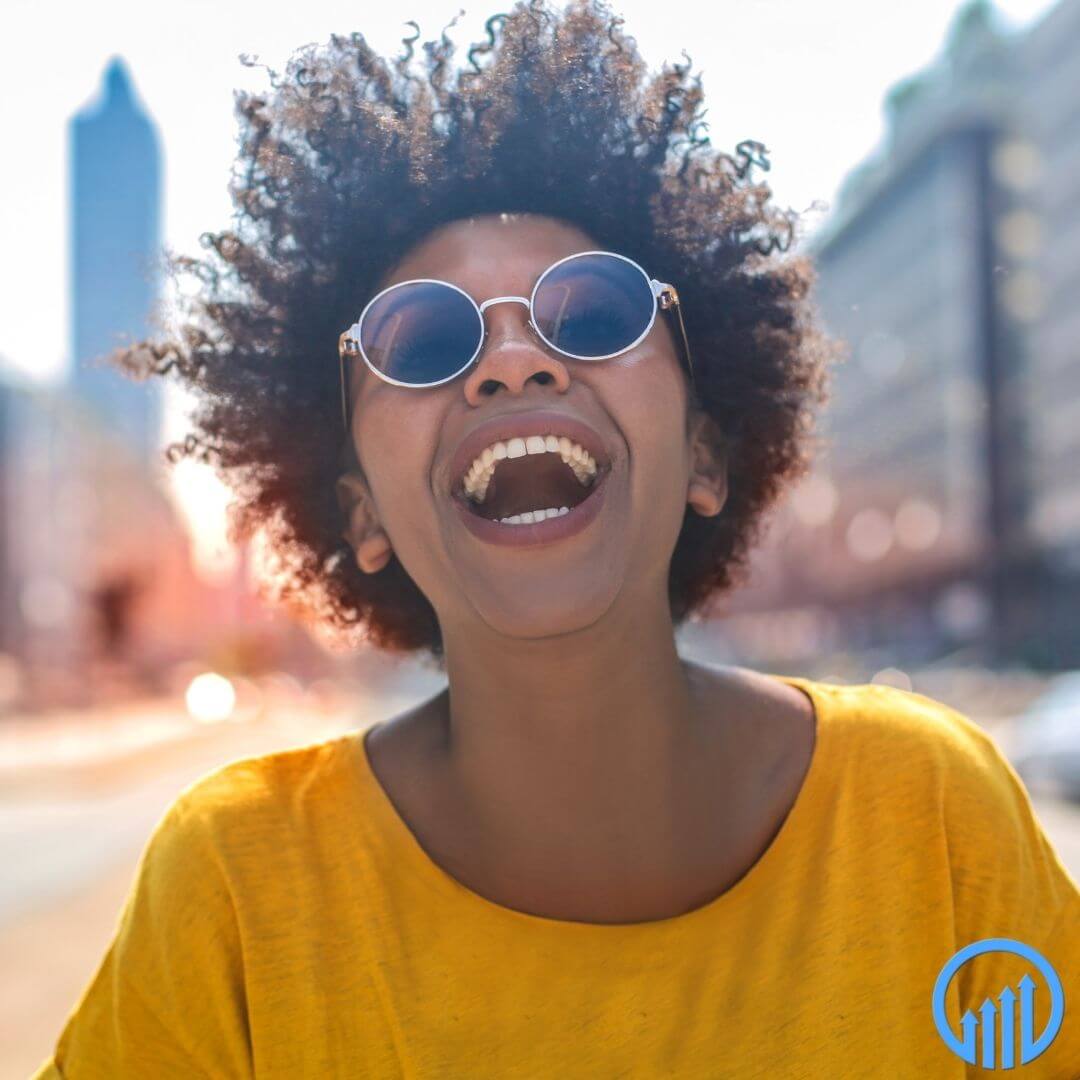 happy African American woman with a yellow shirt and round sunglasses laughing