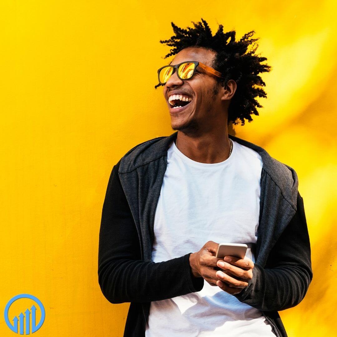 smiling man against a gold background working on his phone