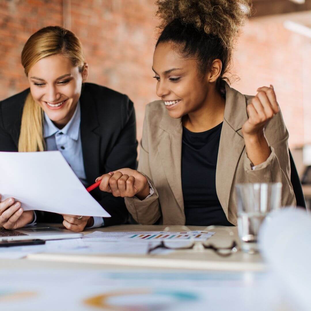 two professional women smiling and working on a marketing project