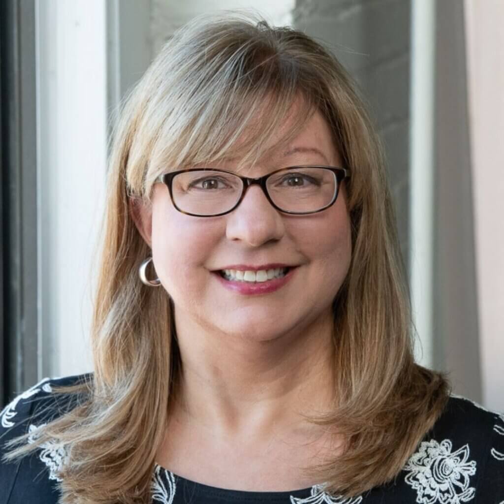 Coach Robin Zaleski smiling, showcasing expertise in marketing and intake systems, with a professional background in client services and business operations.