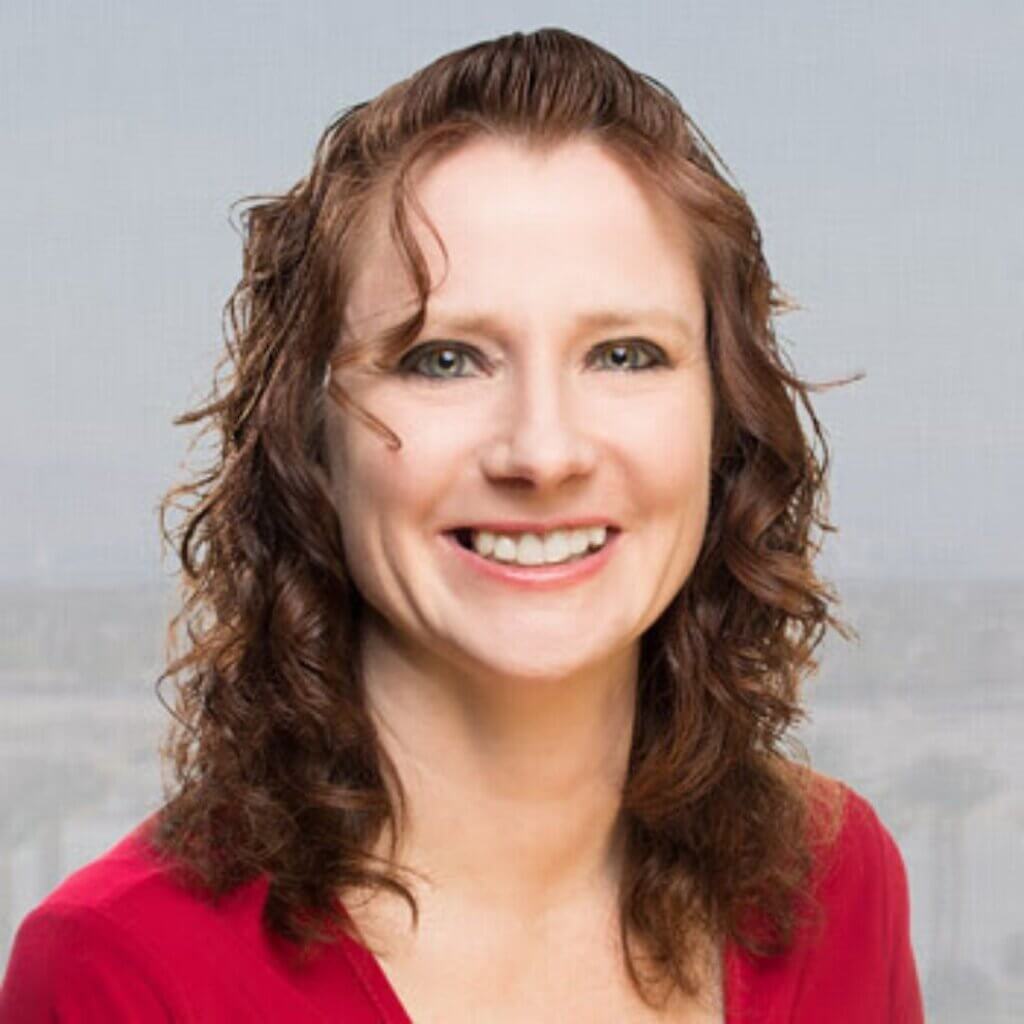 Marie Pues, Financial Controls Coach, smiling with curly hair, wearing a red top, against a neutral background, representing her expertise in bookkeeping and financial organization.