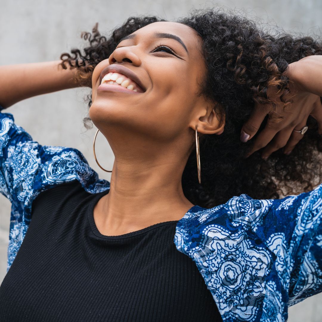 African American woman relaxing and smiling against a gray background