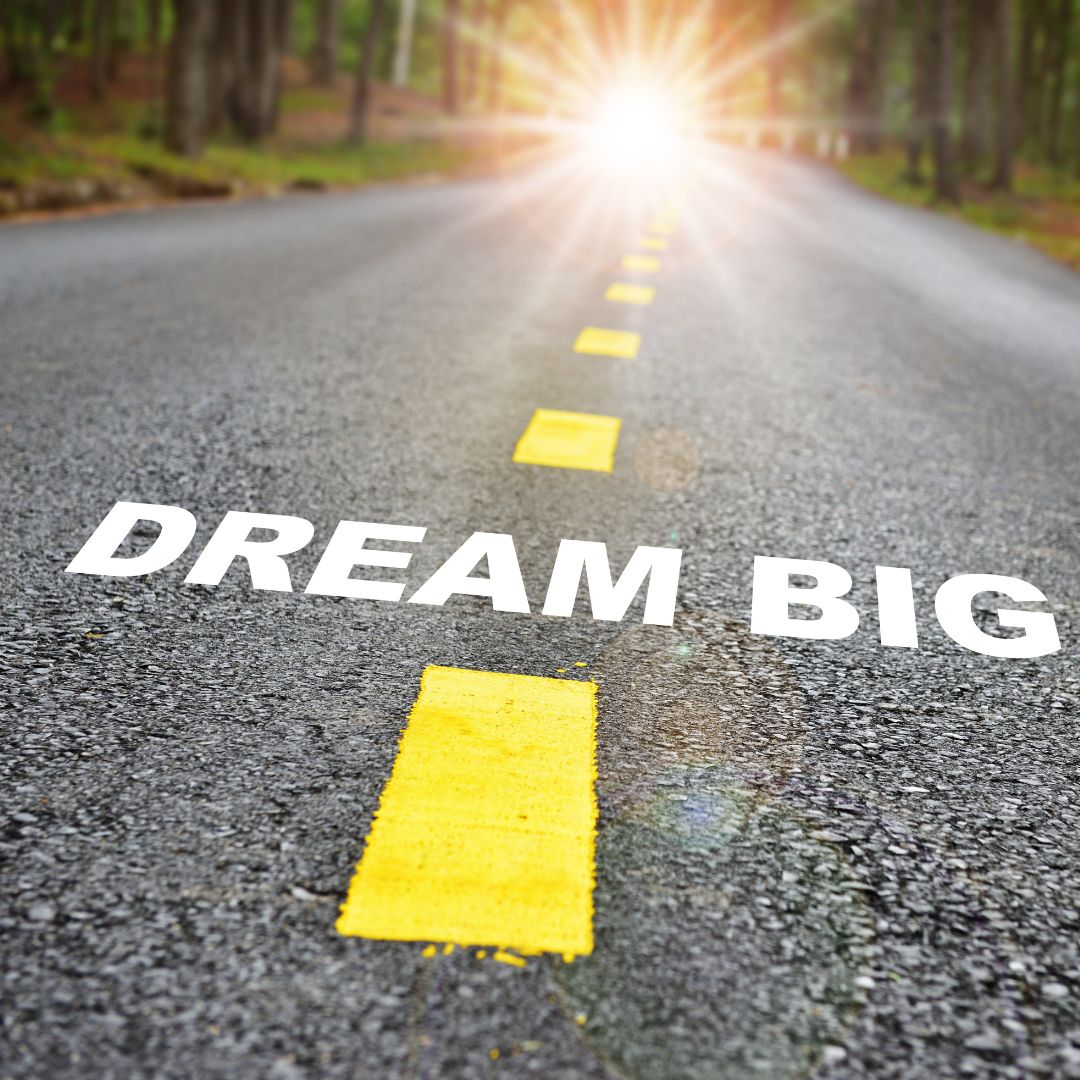 A road in the forest with "Dream Big" painted on it