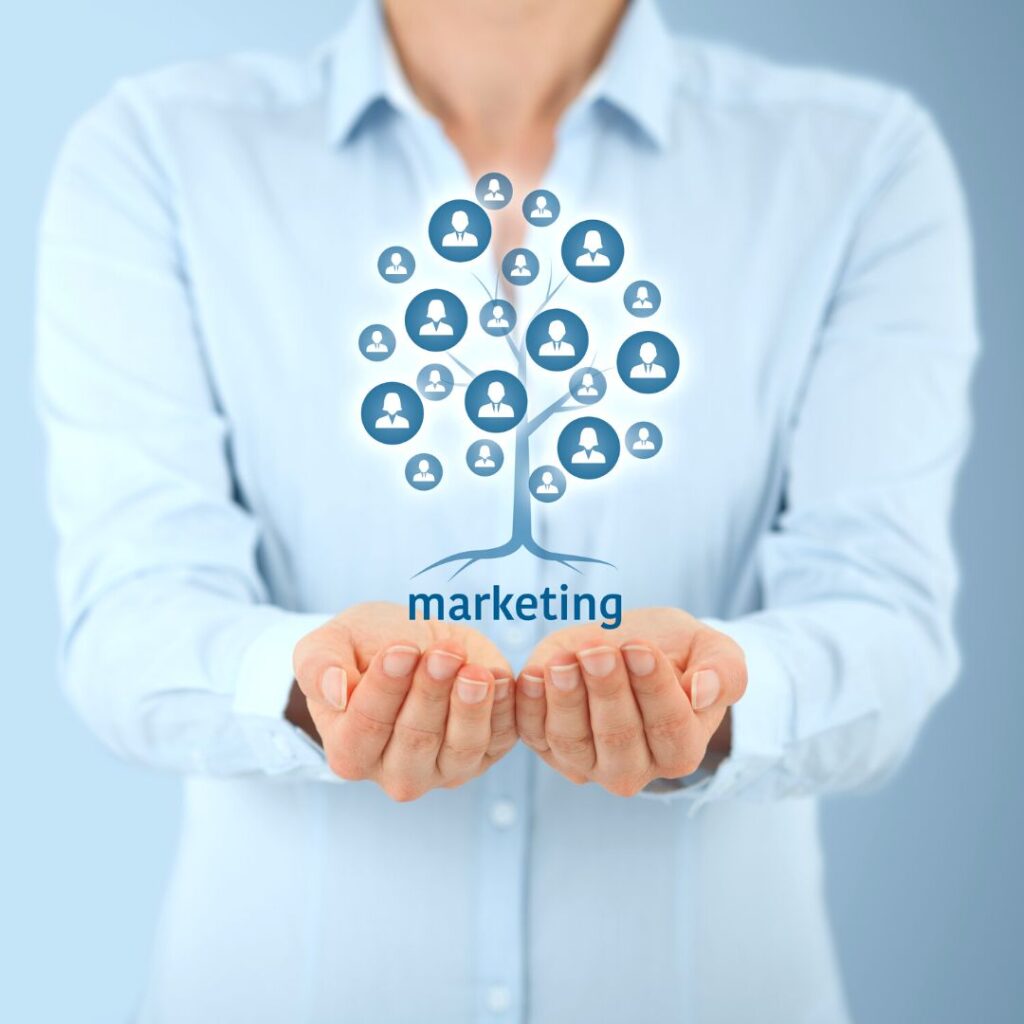 Person holding hands under a graphic tree with marketing icons, symbolizing a proactive marketing team and training for effective campaigns.