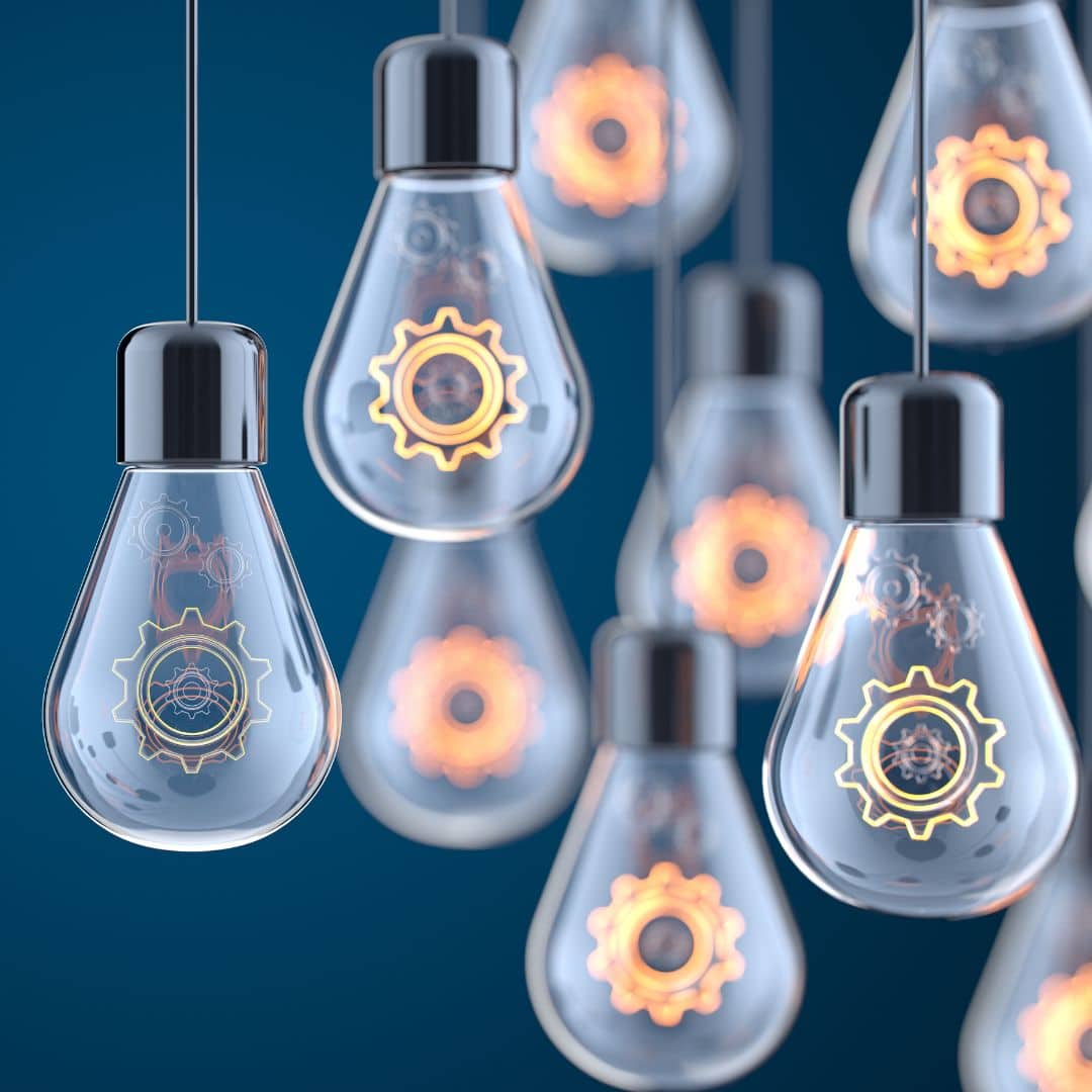 Hanging light bulbs with gear designs, symbolizing innovation and system building for business growth.