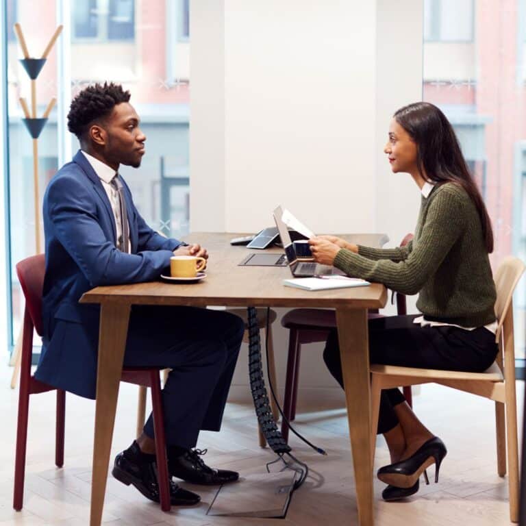 two professionals sitting on opposite sides of a desk discussing a job offer