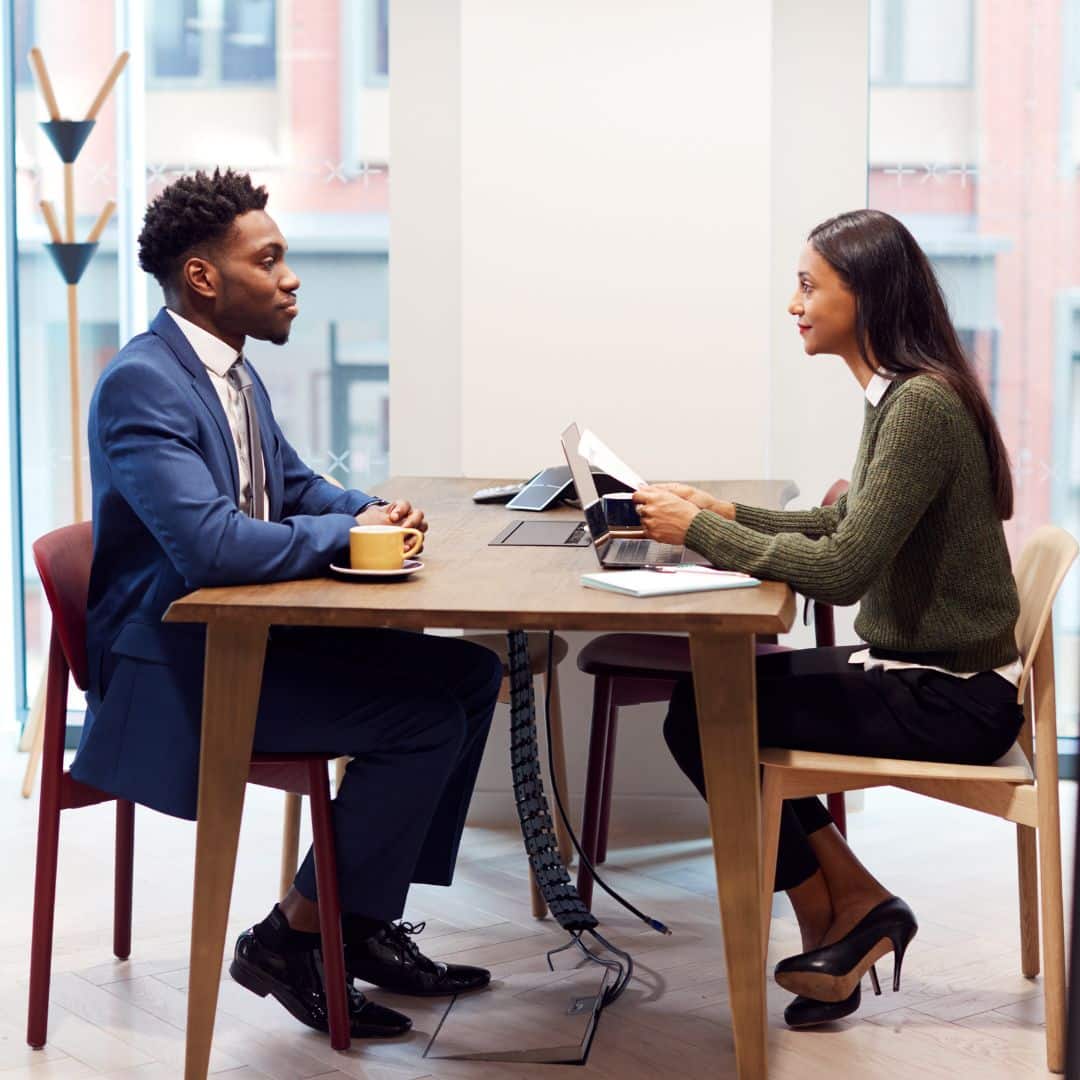 two professionals sitting on opposite sides of a desk discussing a job offer