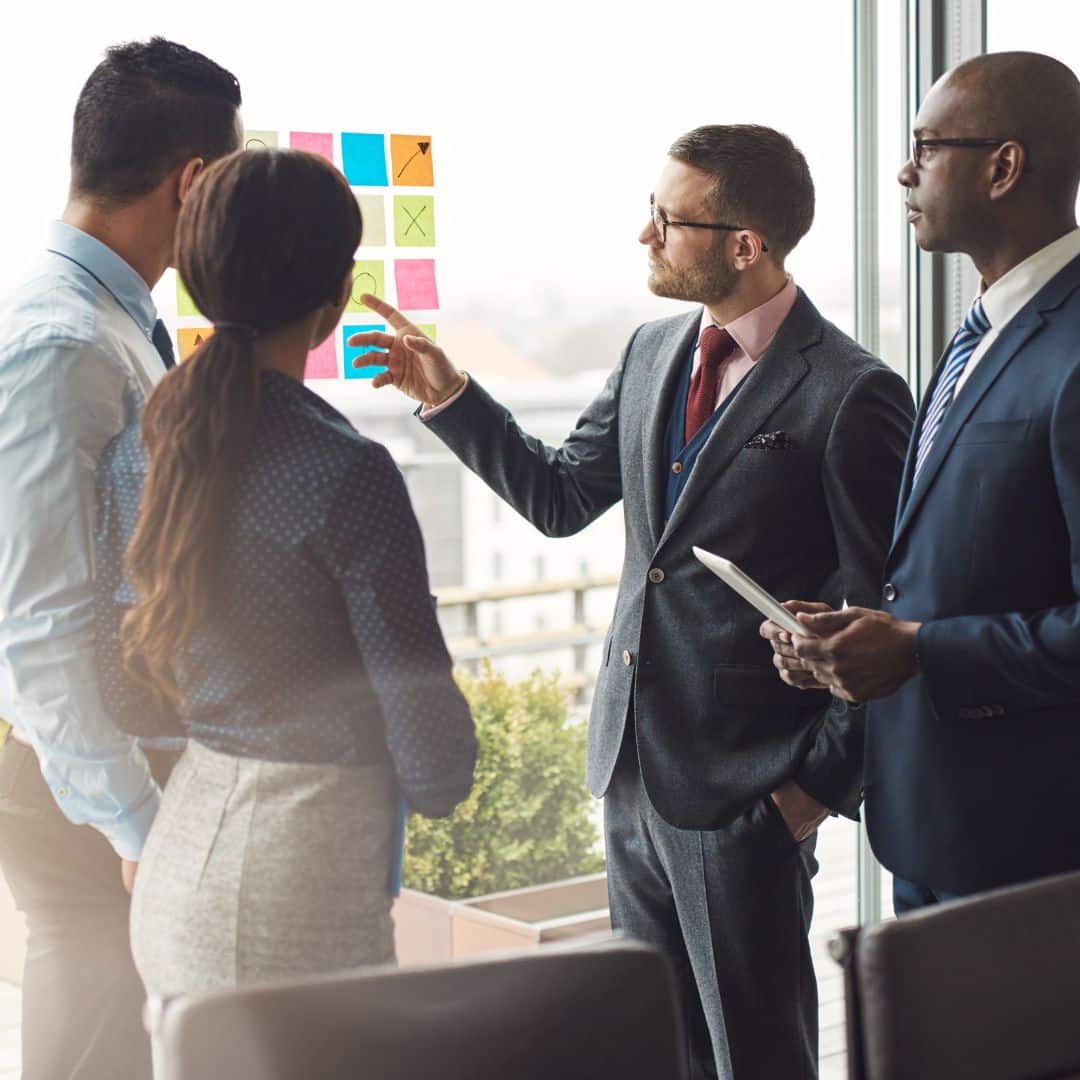 Business team discussing strategy with sticky notes in modern office setting.