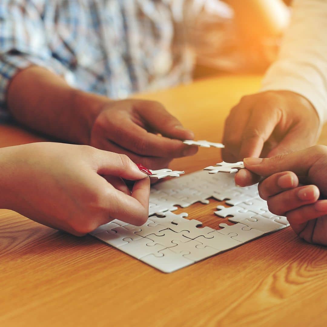 Hands collaborating on a jigsaw puzzle, symbolizing teamwork and collaboration in small business growth.