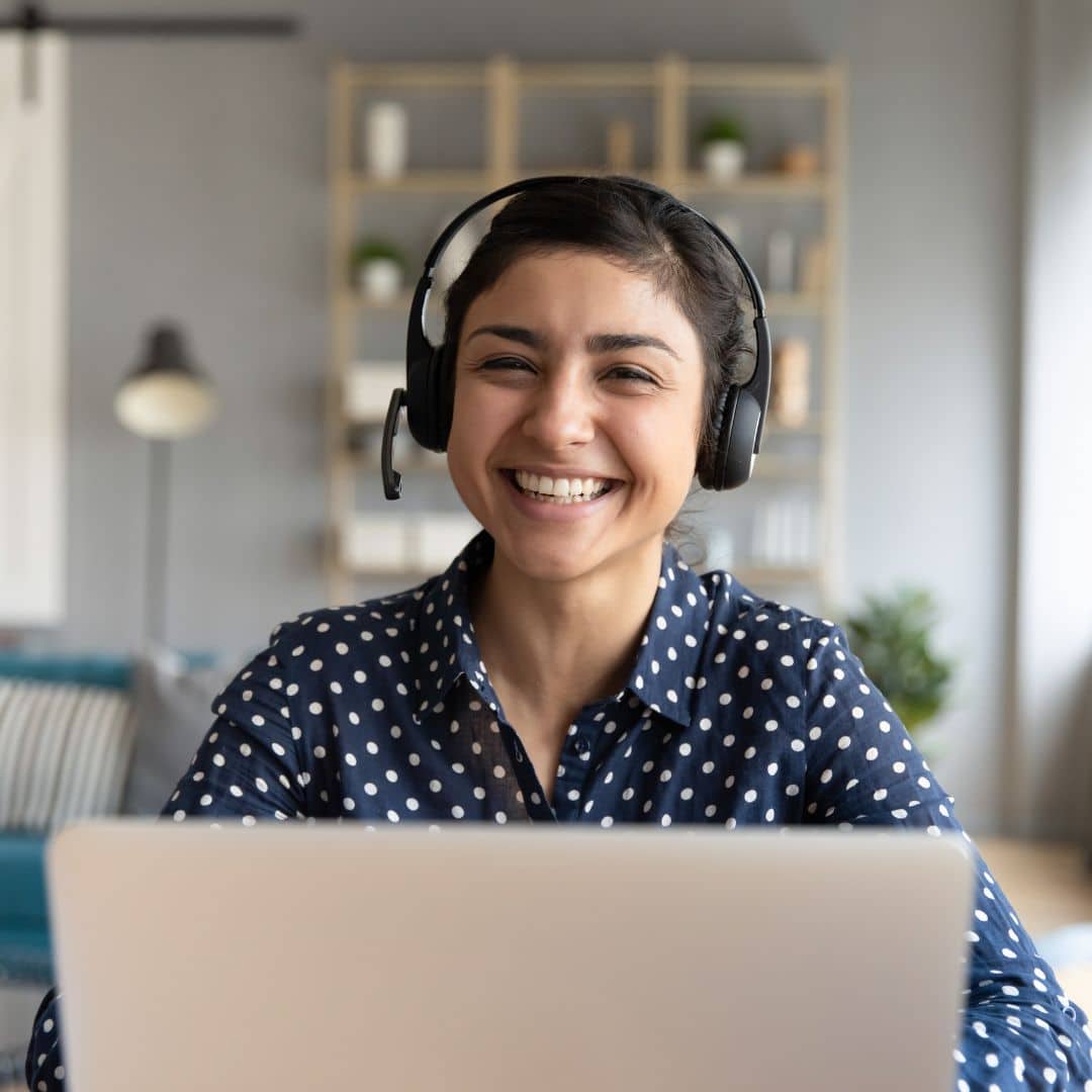 A smiling professional woman with a laptop and headset interacting with a client