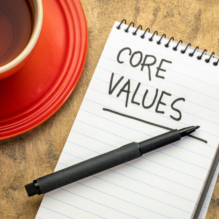 pad of paper with "core values" written on it next to a pen and red coffee mug