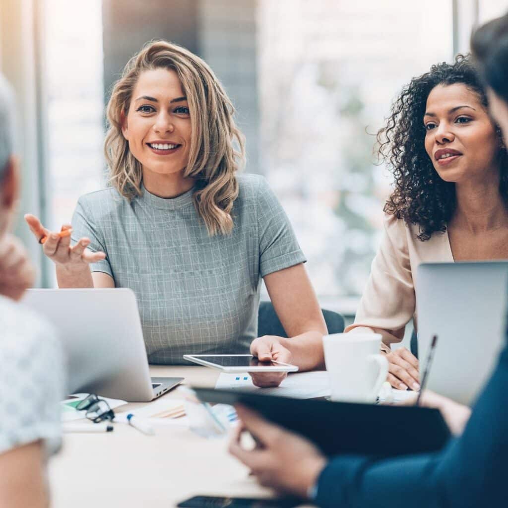 Group of diverse professionals engaged in a collaborative discussion, emphasizing data-driven leadership and team empowerment in a modern office setting.