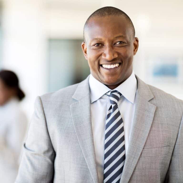Smiling man in a business suit, representing professional development and executive assistant training.