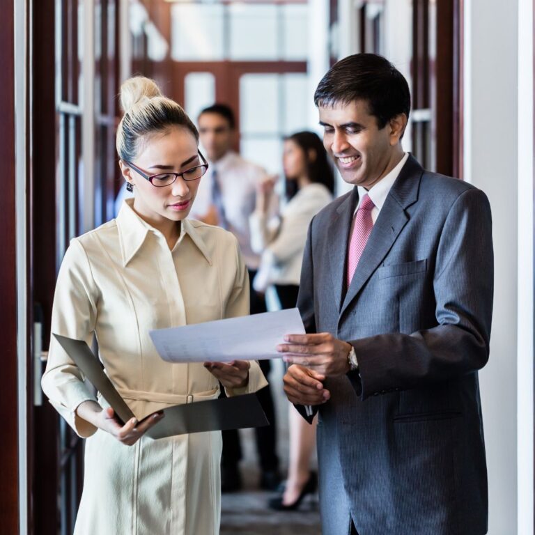A business owner and executive assistant discussing a document.