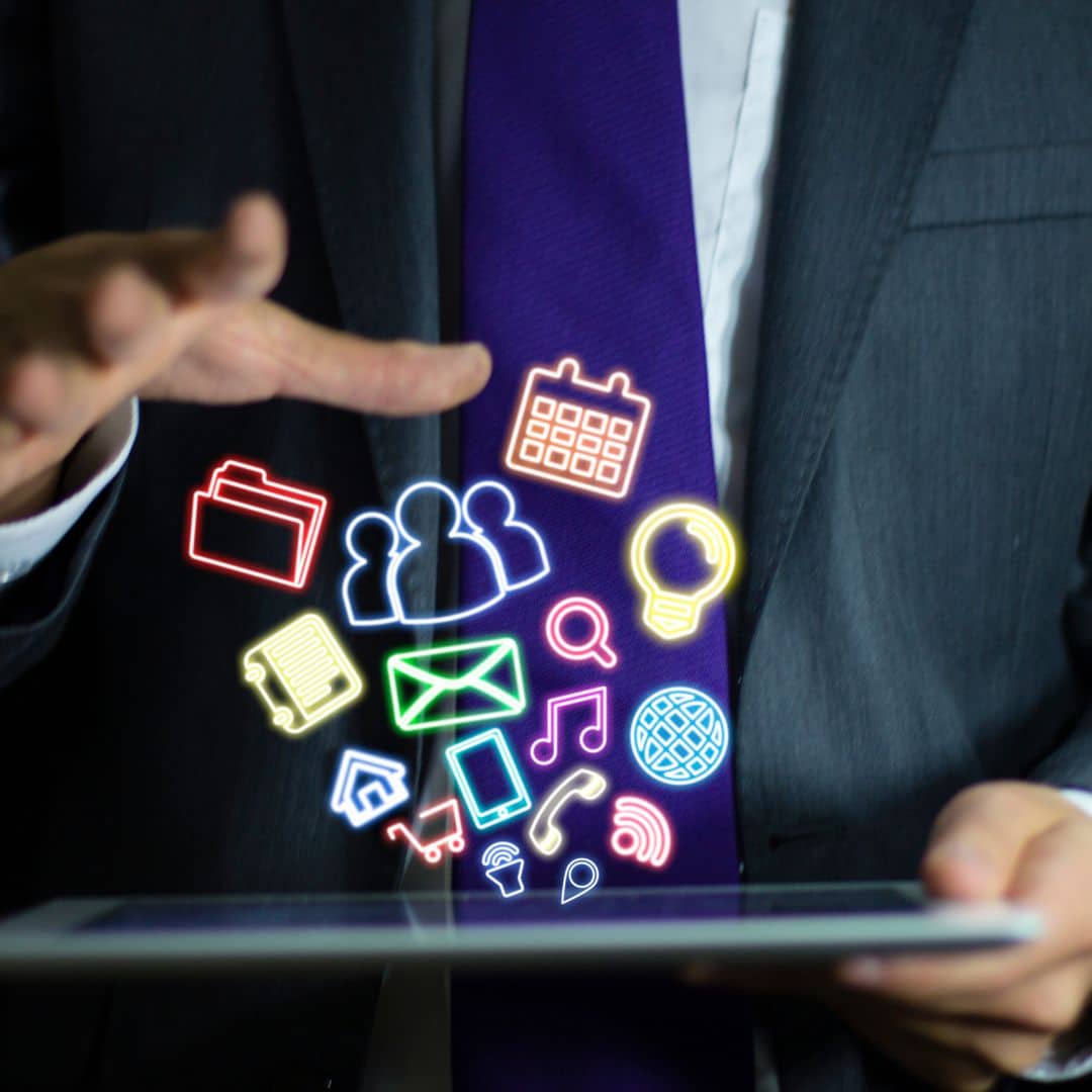 A businessman in a suit and tie working with several icons floating above a tablet