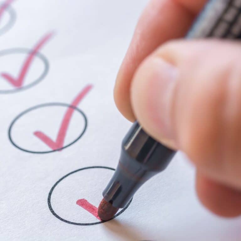 A hand holding a pen, checking off items in a checklist.