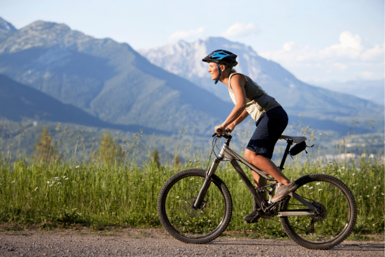 Person biking on a mountain trail, showcasing an active lifestyle and outdoor innovation, surrounded by scenic mountains and greenery.