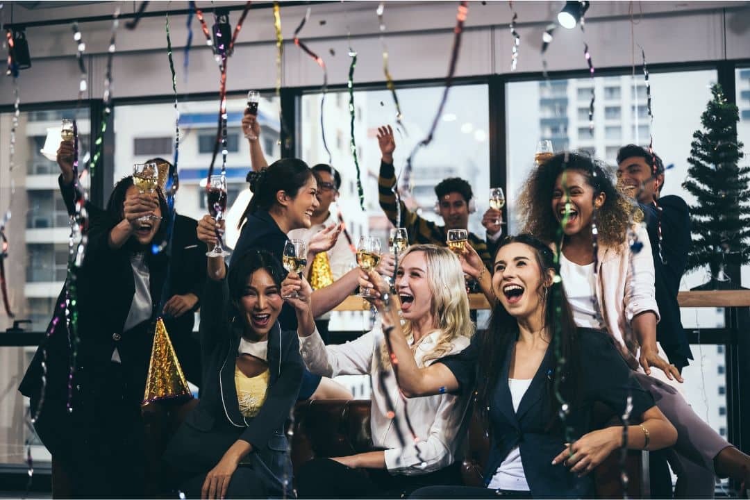 Group of diverse professionals celebrating with drinks and festive decorations, highlighting teamwork and business milestones.