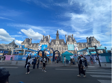 Historic Parisian architecture at the Paris 2024 Olympics site, featuring colorful event branding and crowds enjoying the festivities.