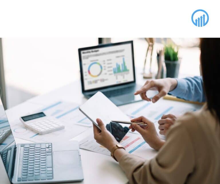 Business professionals analyzing data on digital devices, discussing year-end planning strategies with charts and financial documents on the table.
