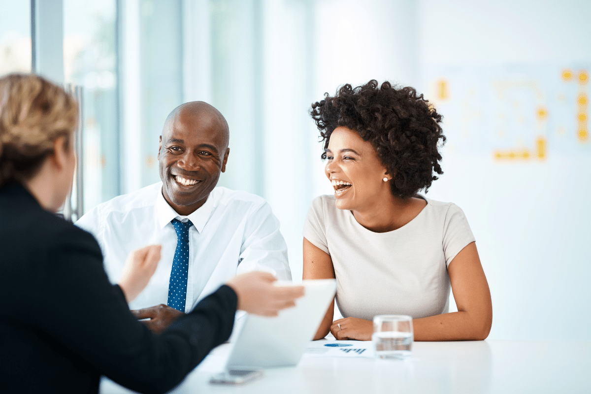 Three professionals engaged in a positive discussion at a table, with a focus on collaboration and client relationships, reflecting the value of effective communication and teamwork in business.